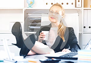 Girl drinking water and lying legs on table