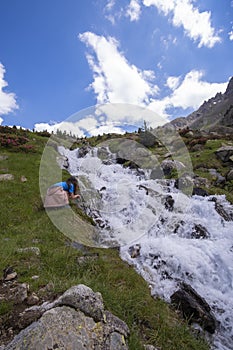 Girl drinking water from a mountain river in the spanish pyrenees