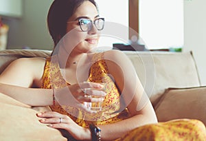 Girl drinking water sitting on a couch at home
