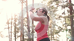 Girl is drinking water in training. The runner controls the water balance in the body.