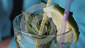 Girl drinks alcoholic mojito drink with mint and lime. Closeup of a glass with mojito