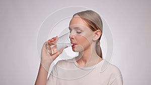 The girl drinks purified mineral water from a glass