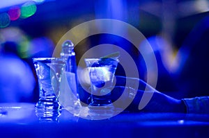 Girl drinks shot of tequila. Limes, salt and shots on table in nightclub. Hand of girl holding glass of alcohol drink in pub. Lady