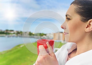 Girl drinks tea on a background sea landscape.