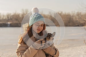 Girl drinks tea from a cup on the street in winter. Owner and pet. girl and chihuahua dog