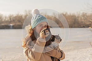 Girl drinks tea from a cup on the street in winter. Owner and pet. Teen girl and chihuahua dog