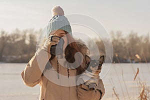Girl drinks tea from a cup on the street in winter. Owner, pet. Teen girl and chihuahua dog