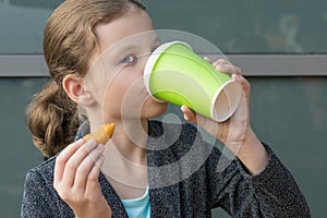 Girl drinks tea and eats fast food in a restaurant
