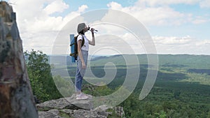 The girl drinks water on peak of the mountain after a long journey to the top.