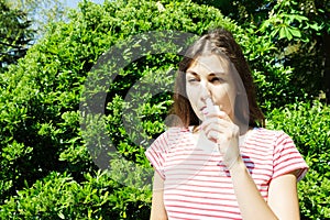 Girl drips blocked nose from allergy. Woman with Respiratory Spray for nose in Spring Blooming. Portrait of a woman having respira