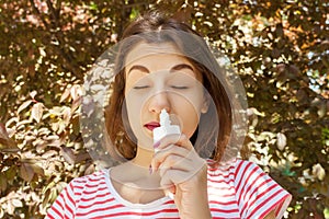 Girl drips blocked nose from allergy. Woman with Respiratory Spray for nose in Spring Blooming. Portrait of a woman having respira photo