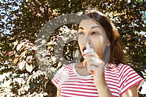 Girl drips blocked nose from allergy. Woman with Respiratory Spray for nose in Spring Blooming. Portrait of a woman having respira photo