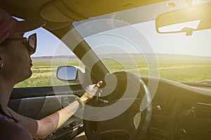 Girl driving on the autobahn, moving towards the sun in a mountainous area, the problem of poor visibility of the road