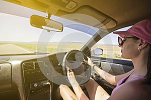 Girl driving on the autobahn, moving towards the sun in a mountainous area, the problem of poor visibility of the road