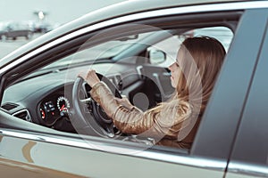 Girl driving car, holds hand, parking shopping center, takes a turn, close-up of the window and door of the car. Leather