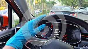 Girl driving a car with one hand in rubber glove on steering wheel