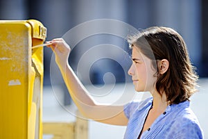 Girl drops a postcard in a mailbox in the Vatican