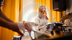 Girl drummer and a guy on keyboards. Focus from hands to drums. Backlight