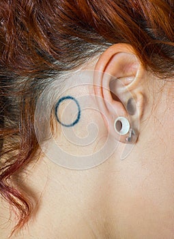 Girl ear with piercings and tattoo