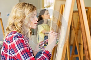 Girl with easel painting at art school studio