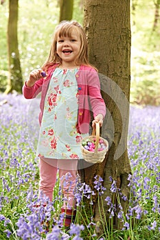Girl On Easter Egg Hunt In Bluebell Woods