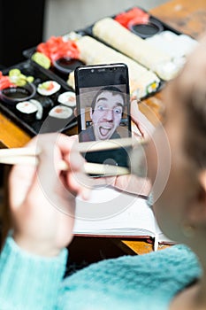 Girl eat sushi and chating with friend. Video call with boyfriend and eat sushi
