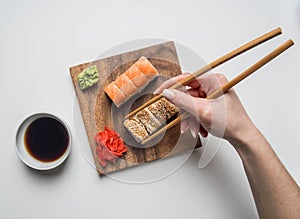 Girl eating an appetizing sushi set with ginger, soy sauce and wasabi on a white background