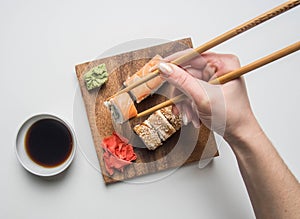 Girl eating an appetizing sushi set with ginger, soy sauce and wasabi on a white background