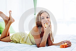 Girl eating apple and relaxing in bedroom