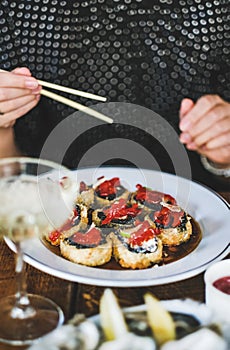 Girl eating baked susi maki with chopsticks at Japanese restaurant