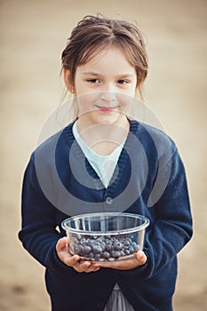 The girl eating blueberries from a glass bowl