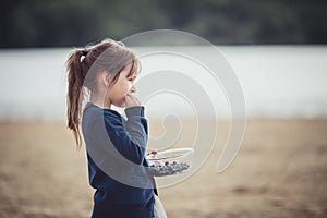 The girl eating blueberries from a glass bowl