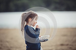 The girl eating blueberries from a glass bowl