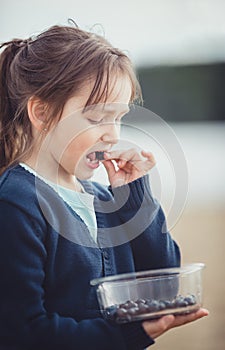 The girl eating blueberries from a glass bowl