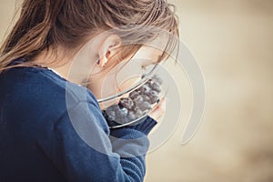 The girl eating blueberries from a glass bowl