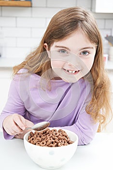 Girl Eating Bowl Of Sugary Breakfast Cereal In Kitchen