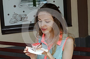 Girl is eating a cake in an outdoor cafe