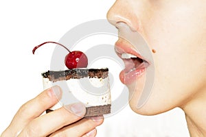 Girl eating chocolate cake with cherry on the top icing