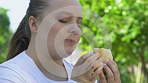 Girl eating fatty high calorie burger, fast food addiction, lack of willpower