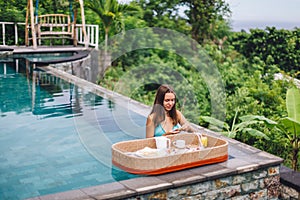 Girl eating floating breakfast in luxury infinity pool