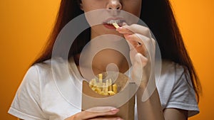 Girl eating french fries, enjoying fast food, high calorie meal, risk of obesity