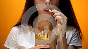 Girl eating french fries, enjoying fast food, high calorie meal, risk of obesity