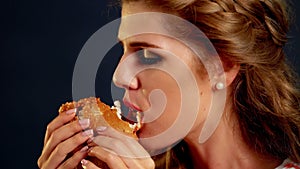 Girl eating hamburger. Hungry young woman gobbles with appetite.