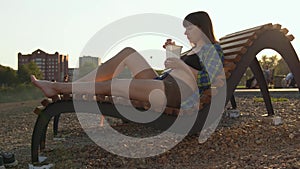 Girl eating hot noodles on the pebble beach of the river bank.