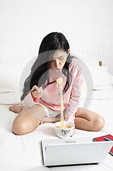 Girl eating instant noodle while running her business at home in