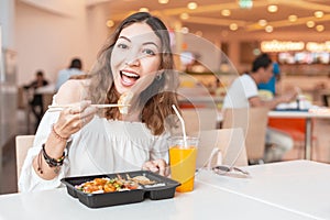 Girl eating Japanese Gyoza dumplings in food court during lunch break