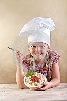Girl eating pasta with tomato sauce and basil