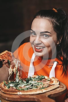 girl eating pizza. a girl in an orange sweater eats pizza appetizingly. stretching cheese, tasty, juicy.