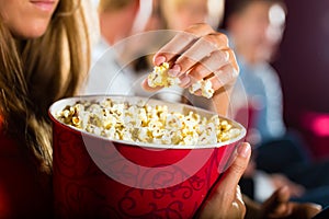 Girl eating popcorn in cinema or movie theater photo