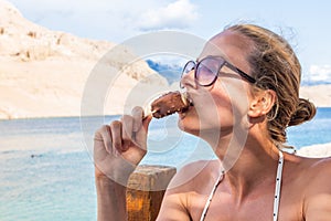 Girl eating popsicle ice pop in shade on picture perfect beach in summer.